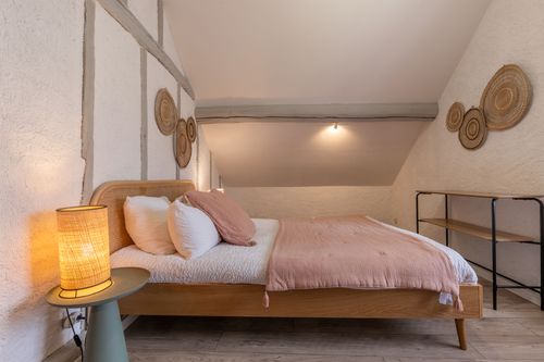 The double bed with a pink bedspread in the timber-framed bedroom
