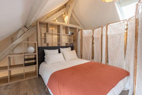 The attic bedroom with a terracotta bedspread beside an openwork partition