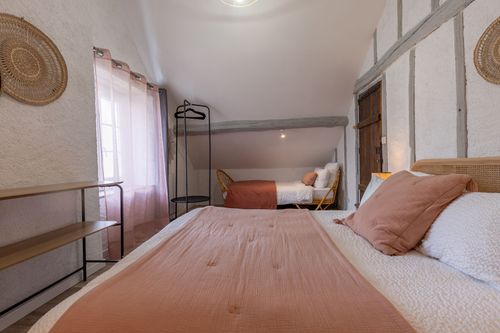 The pink-toned bedroom with a double bed and an additional bed at the back