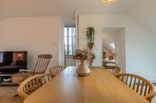 The large wooden table and chairs, with the lounge in the background