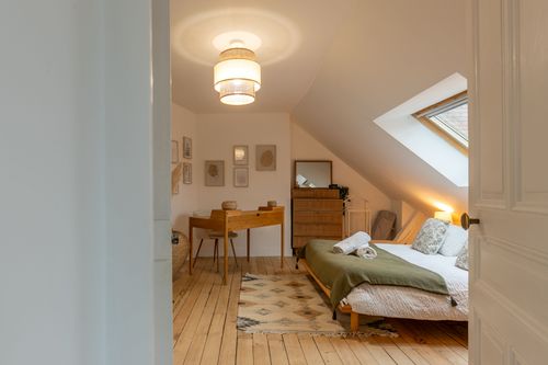 The attic bedroom seen from the corridor, with a double bed and desk