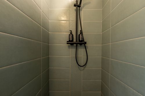 The green-tiled shower with black shower fittings