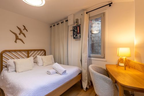 The bedroom with decorative birds, a rattan headboard and desk