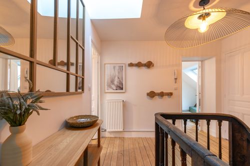 The bright landing with a wooden console table and wall hooks