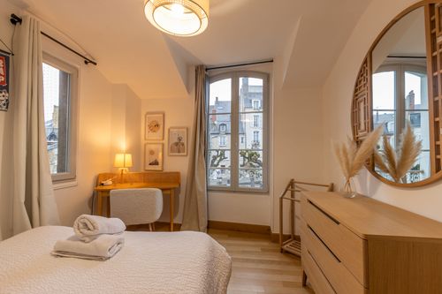 The double bed and desk near the window in the second bedroom