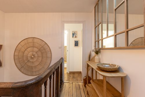 The wooden landing with a console table and large lattice-framed mirror