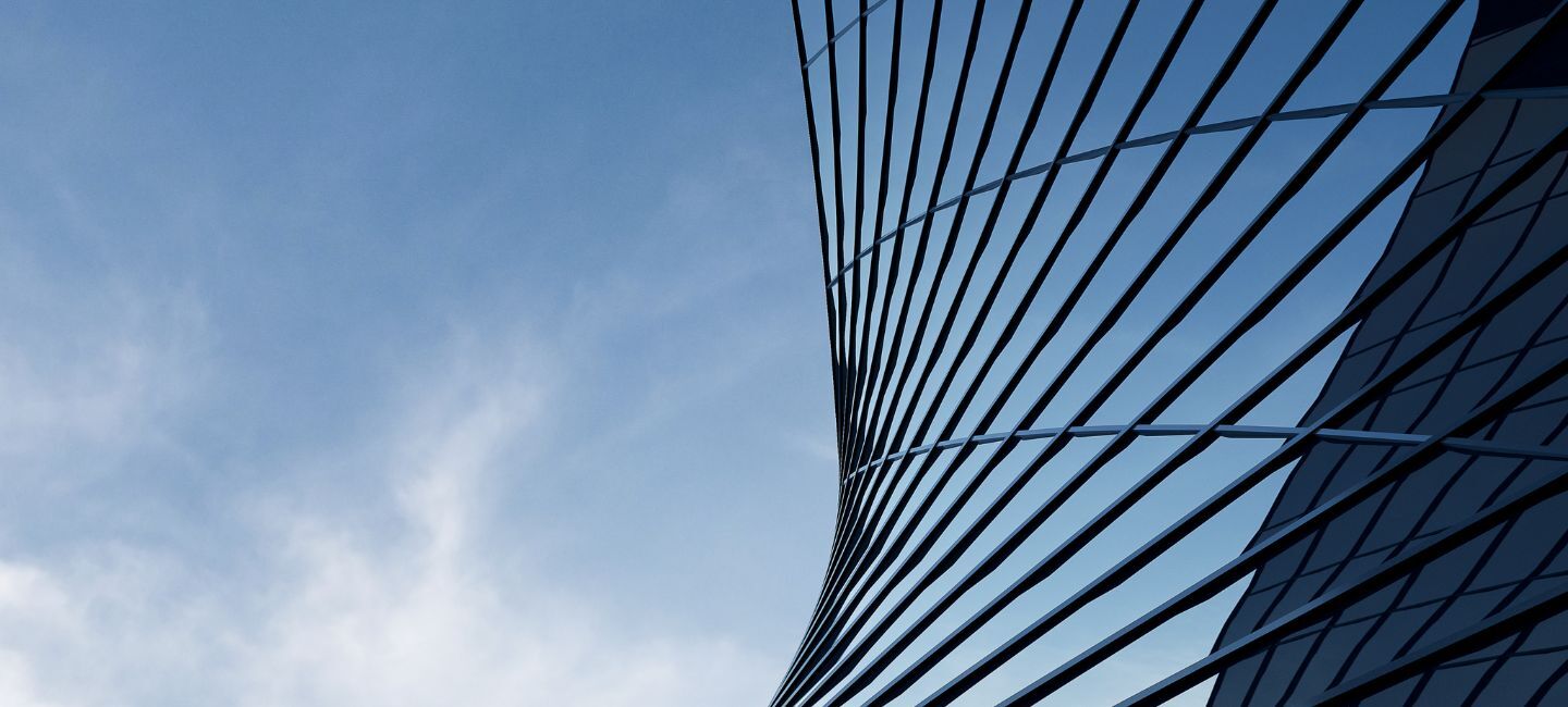 Moderne geschwungene Glasfassade vor blauem Himmel