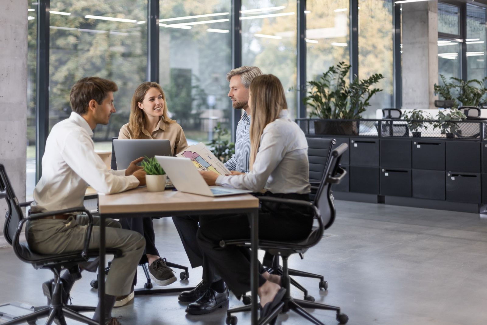Vier Personen arbeiten gemeinsam an einem Tisch in einem modernen Büro.