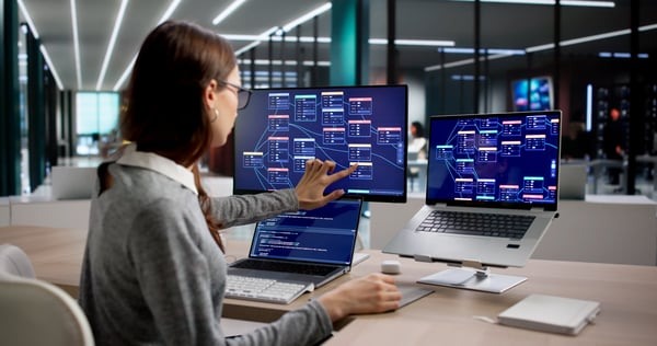 Person betrachtet vernetzte digitale Arbeitsabläufe an mehreren Bildschirmen