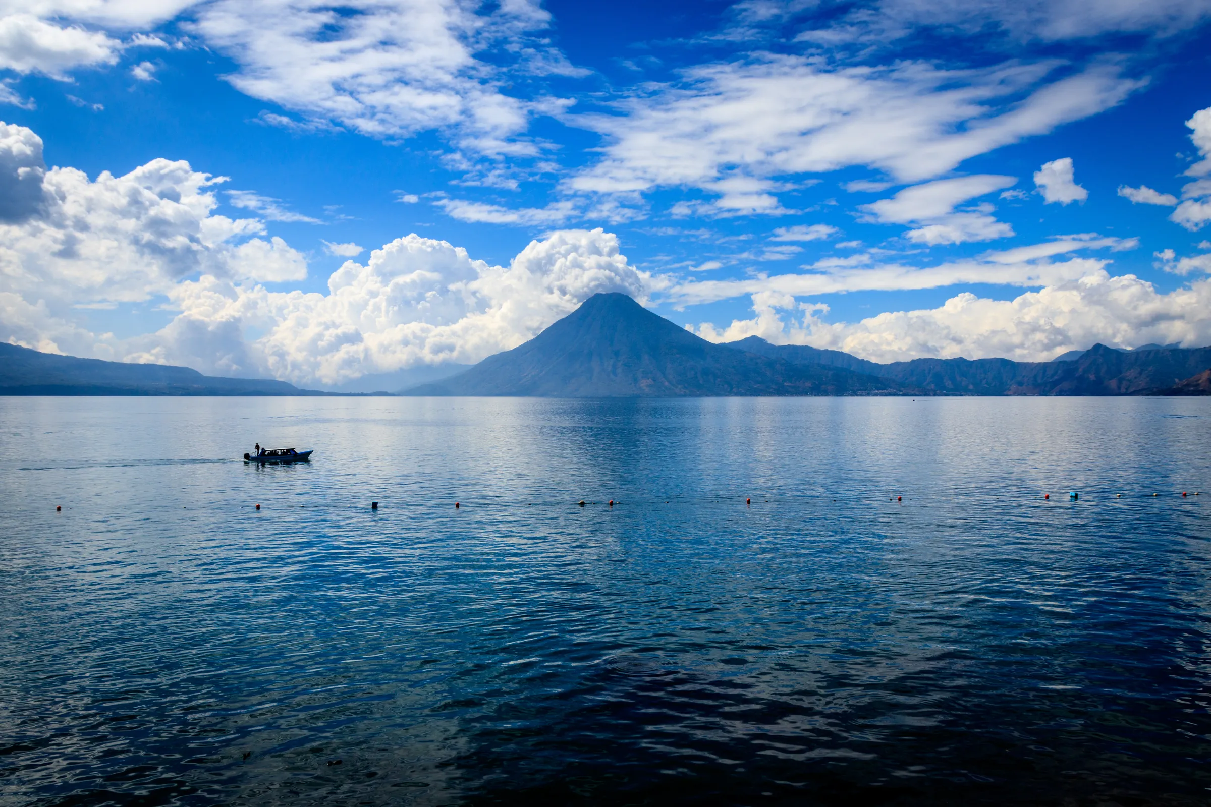 Lone boat on Lake Atitlán below a volcano