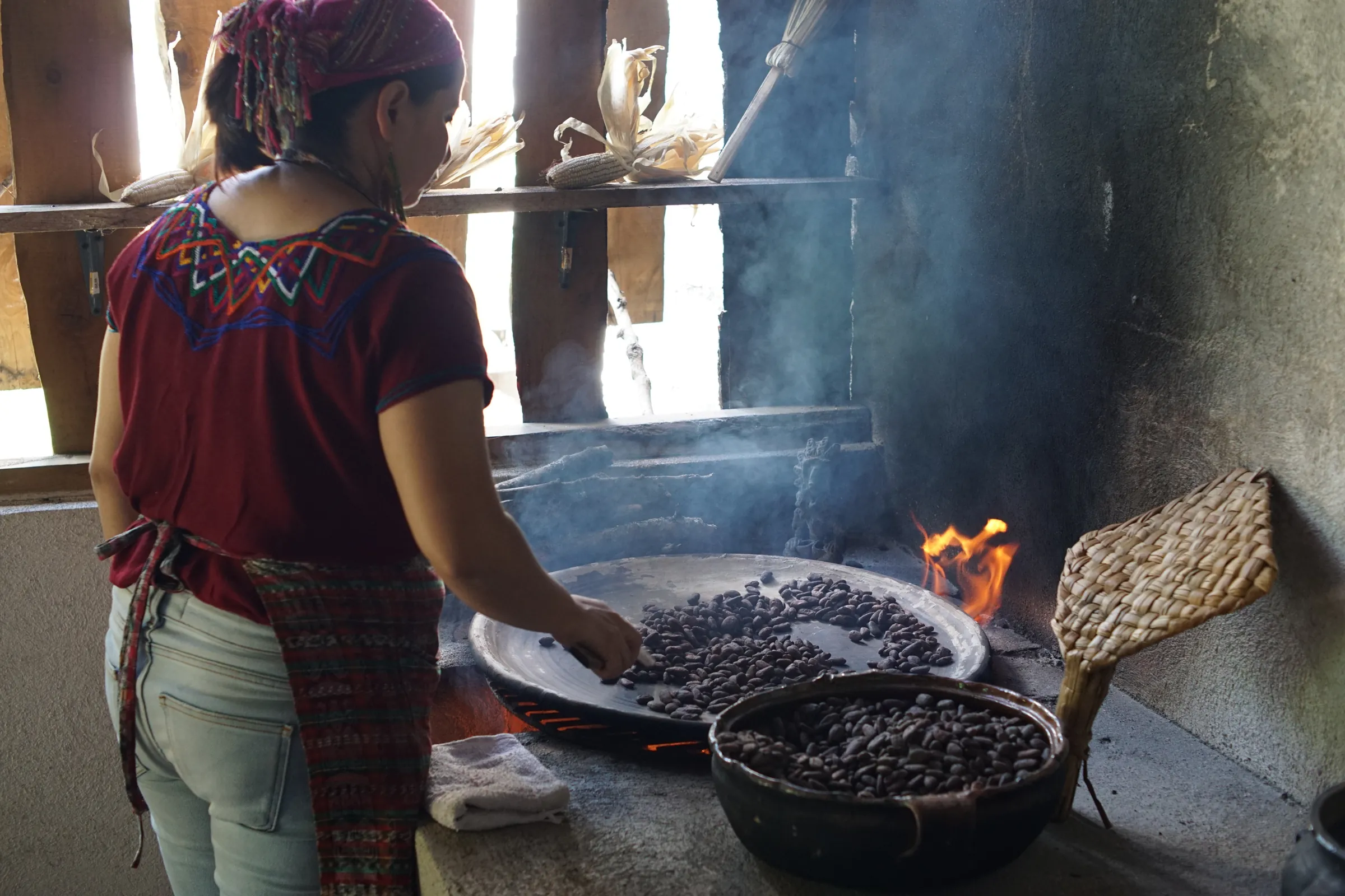 Woman roasting beans over a wood fire, Guatemala
