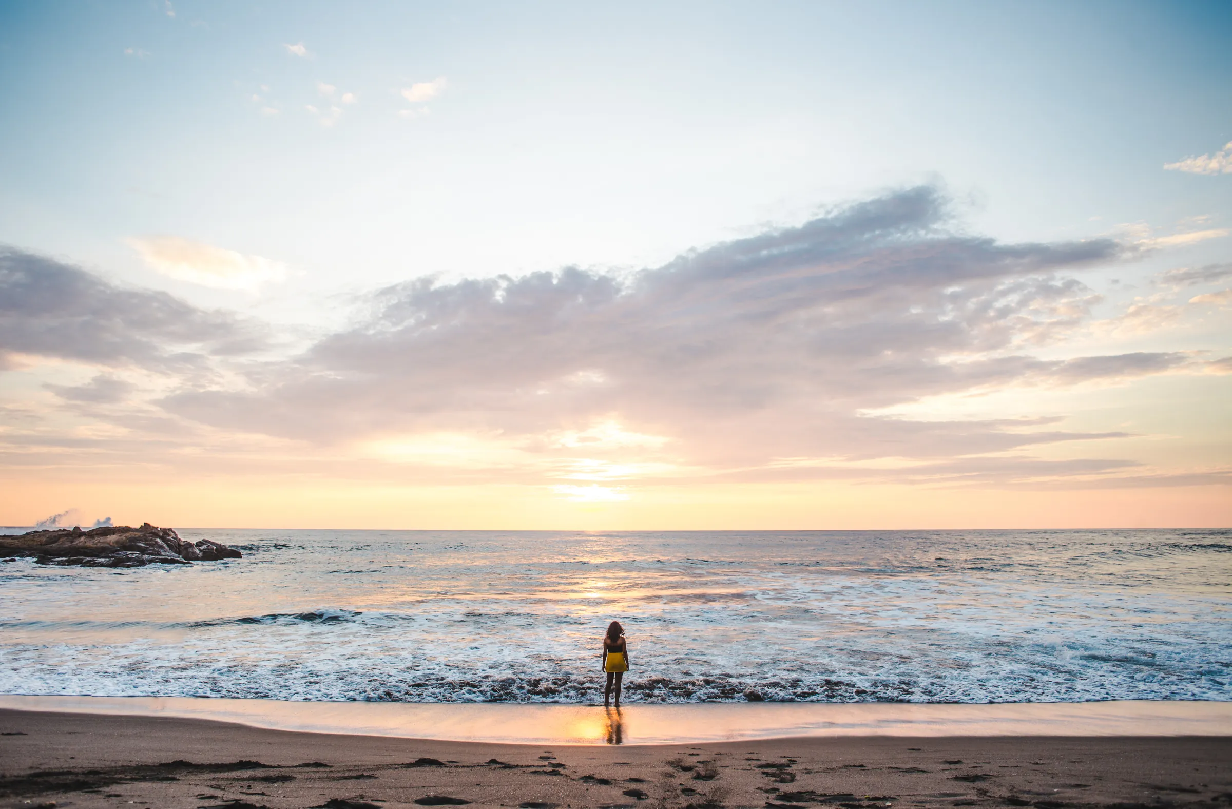 Woman at the surf line under a pastel sunset, Nicaragua