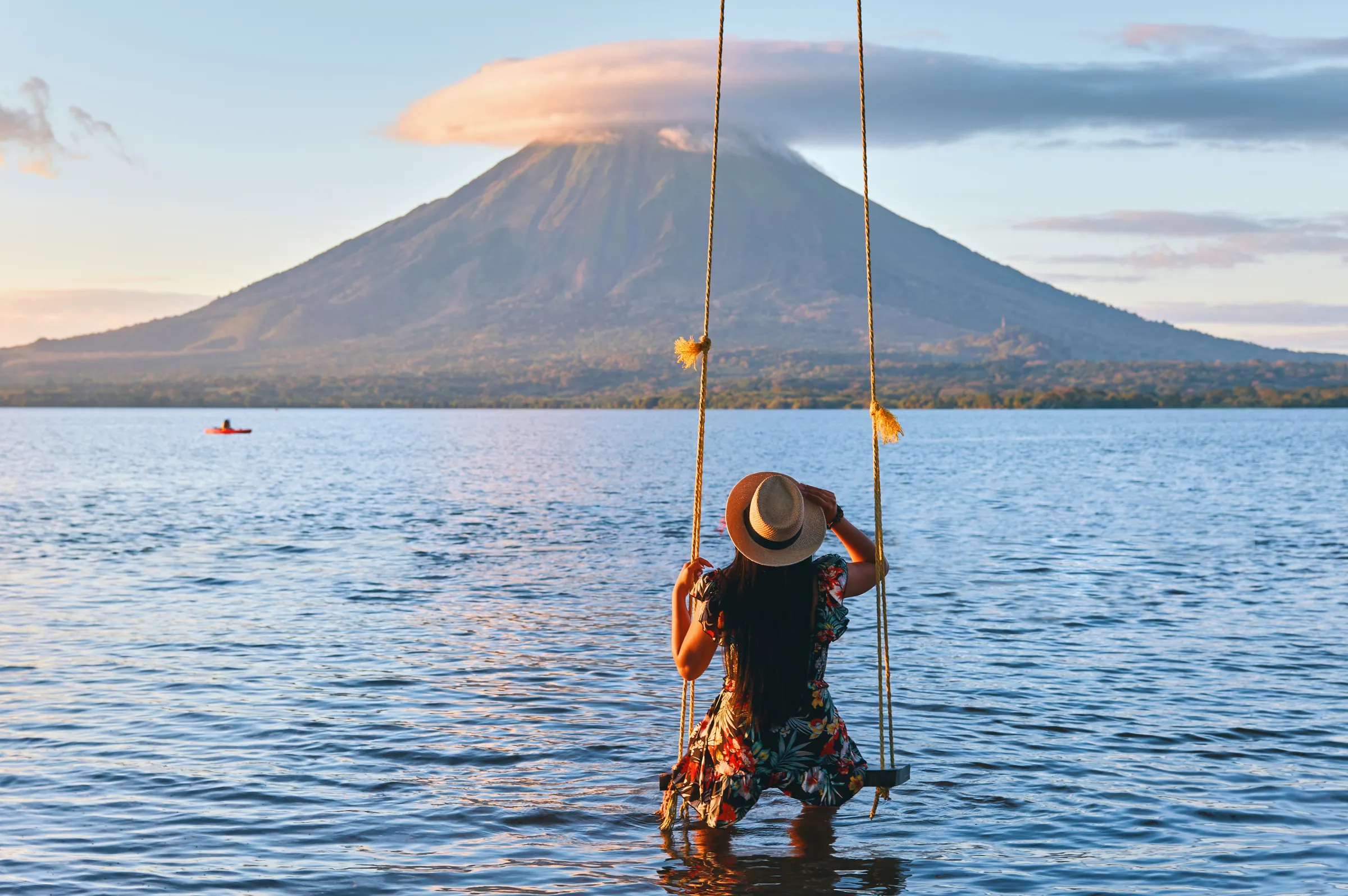 Woman on a swing above Lake Nicaragua facing Concepción Volcano, Ometepe