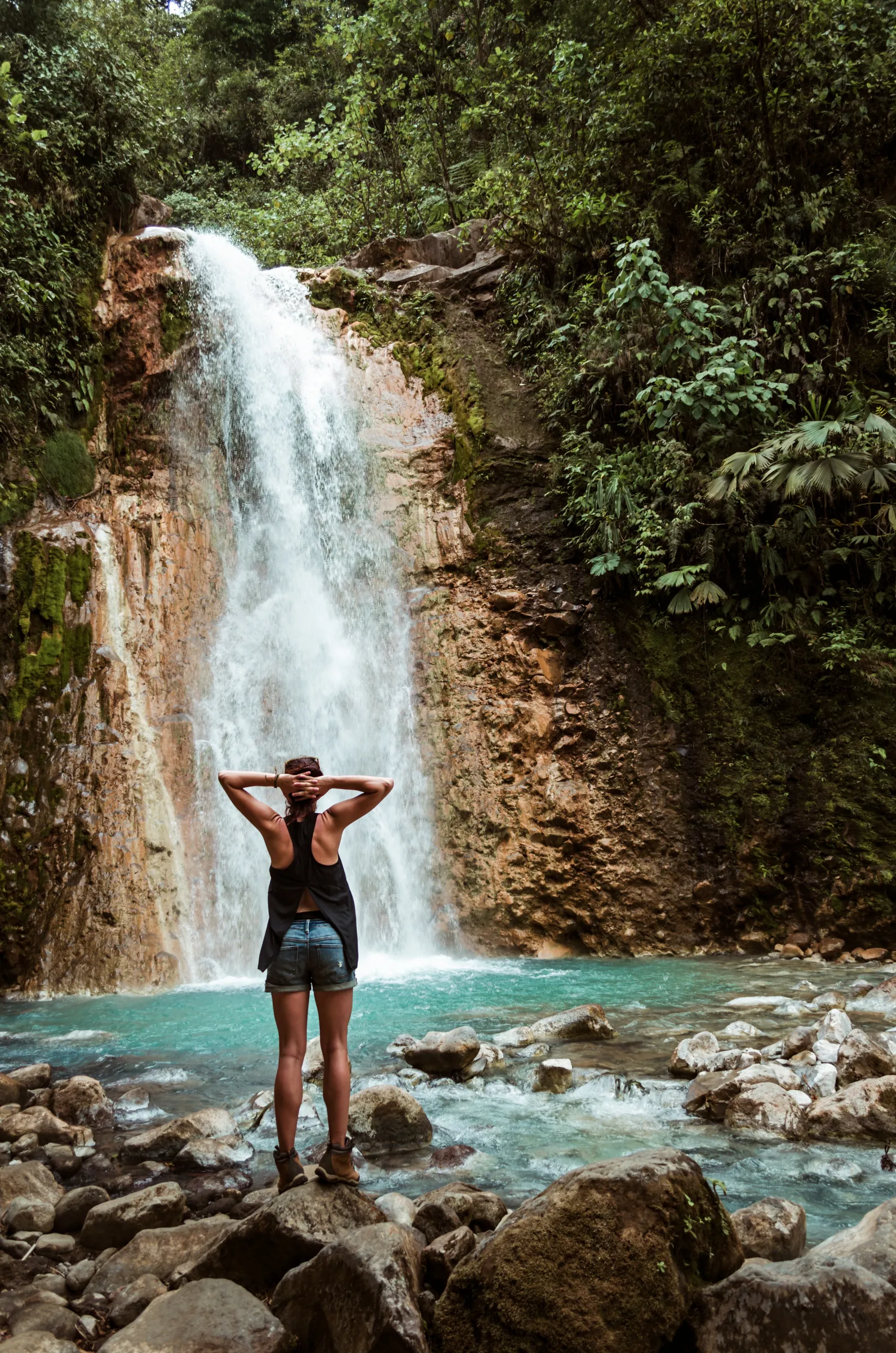 Woman swimming beneath a rainforest waterfall in Costa Rica