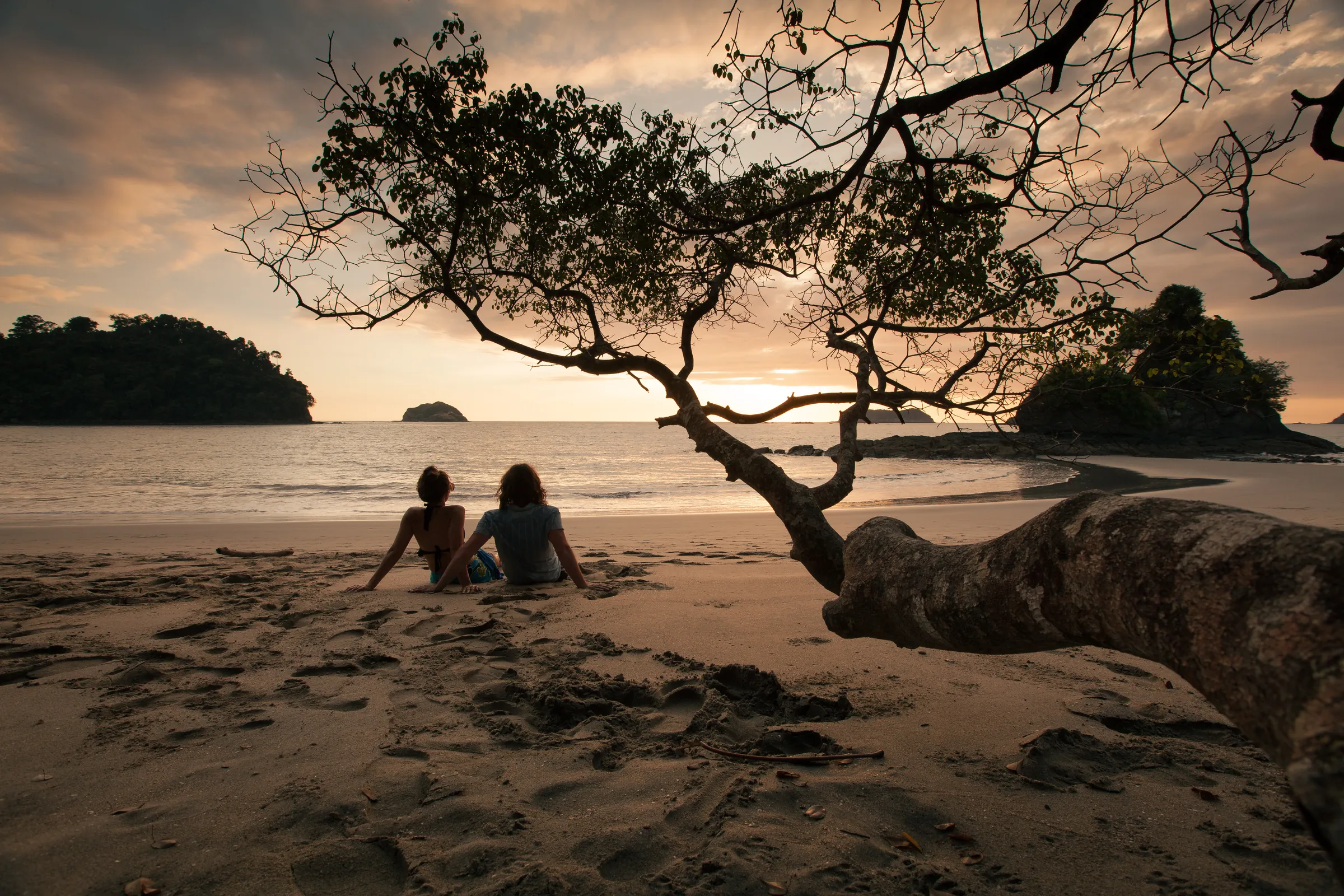 Couple on a Costa Rica beach at sunset with islands offshore