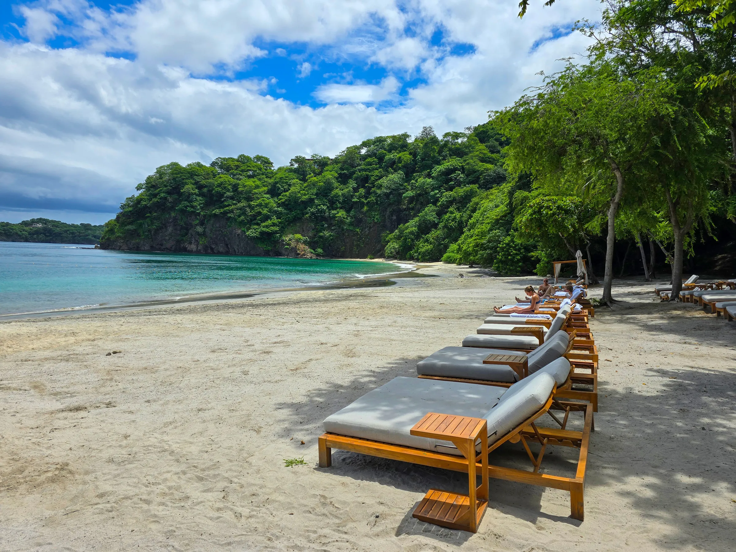 Beach loungers in a quiet forested cove in Costa Rica