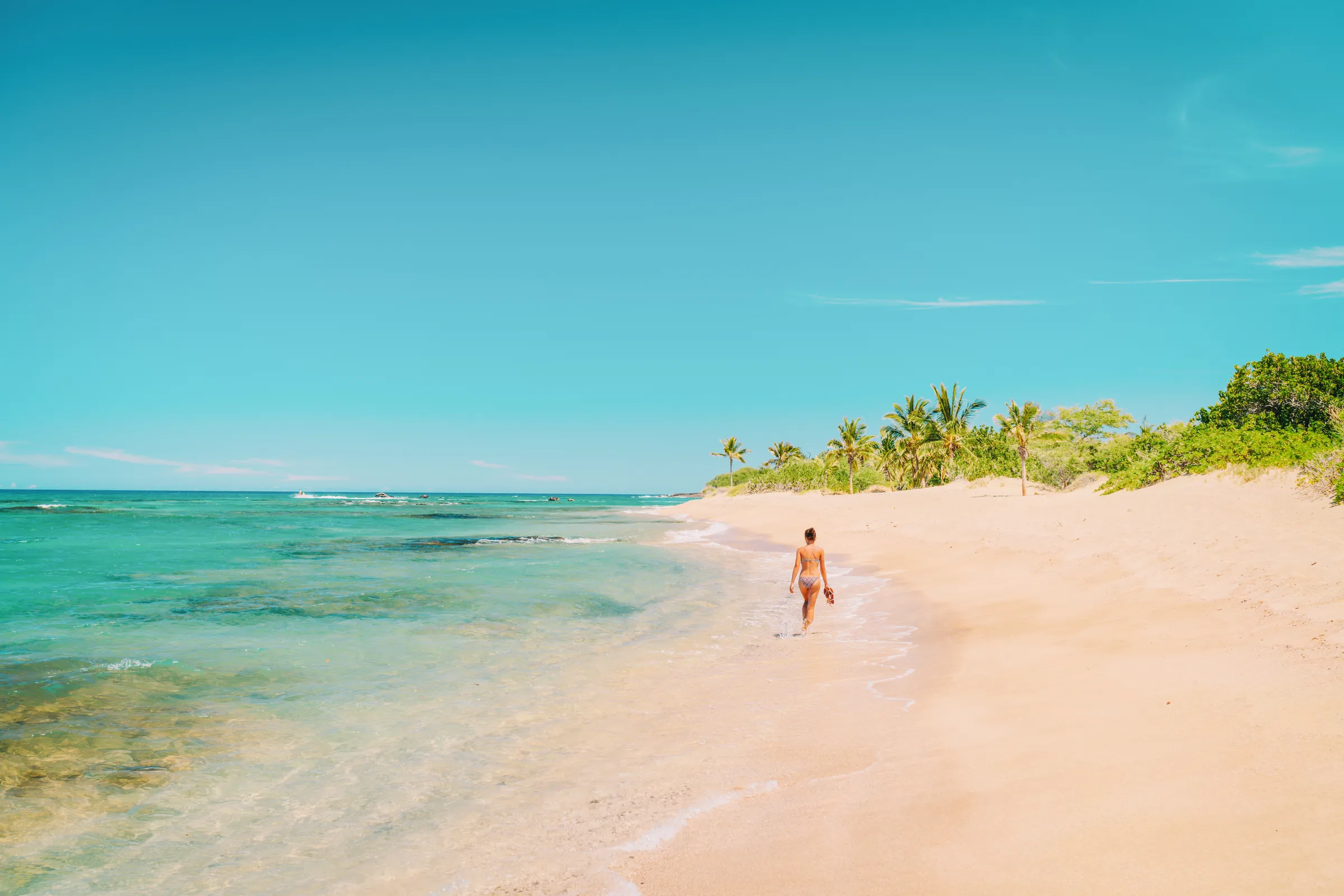 Woman walking along a turquoise beach in Costa Rica