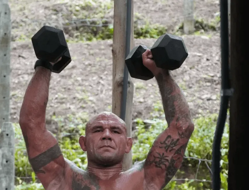 Athlete lifting dumbbells overhead at Jungle's Edge