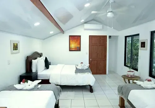 Casita room with a queen bed and two single beds under a vaulted ceiling