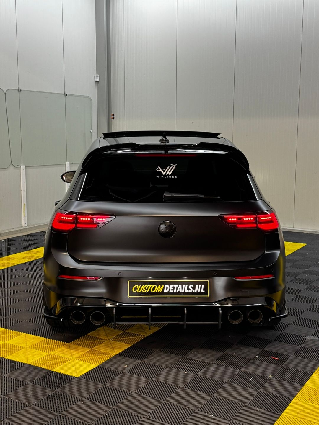 Achterkant van de Volkswagen Golf R in satijn zwart in de werkplaats