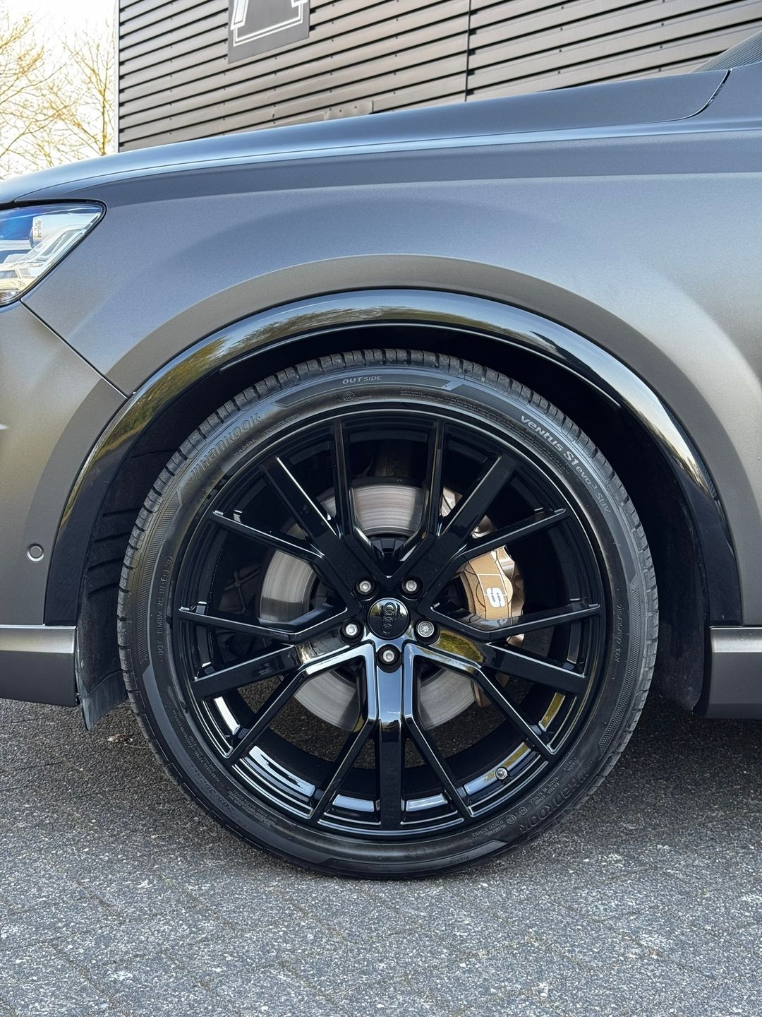 Audi Q7 in satijn grijs, detail van zwarte velg en glanzend zwarte wielkastrand