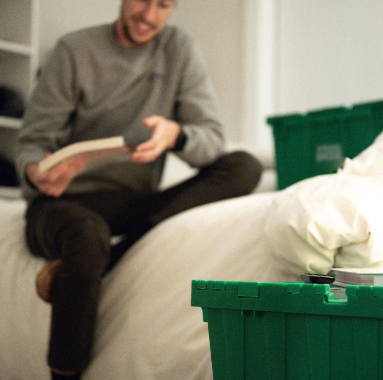 Soft-focus photo of a person packing a book at home beside green Frogbox bins