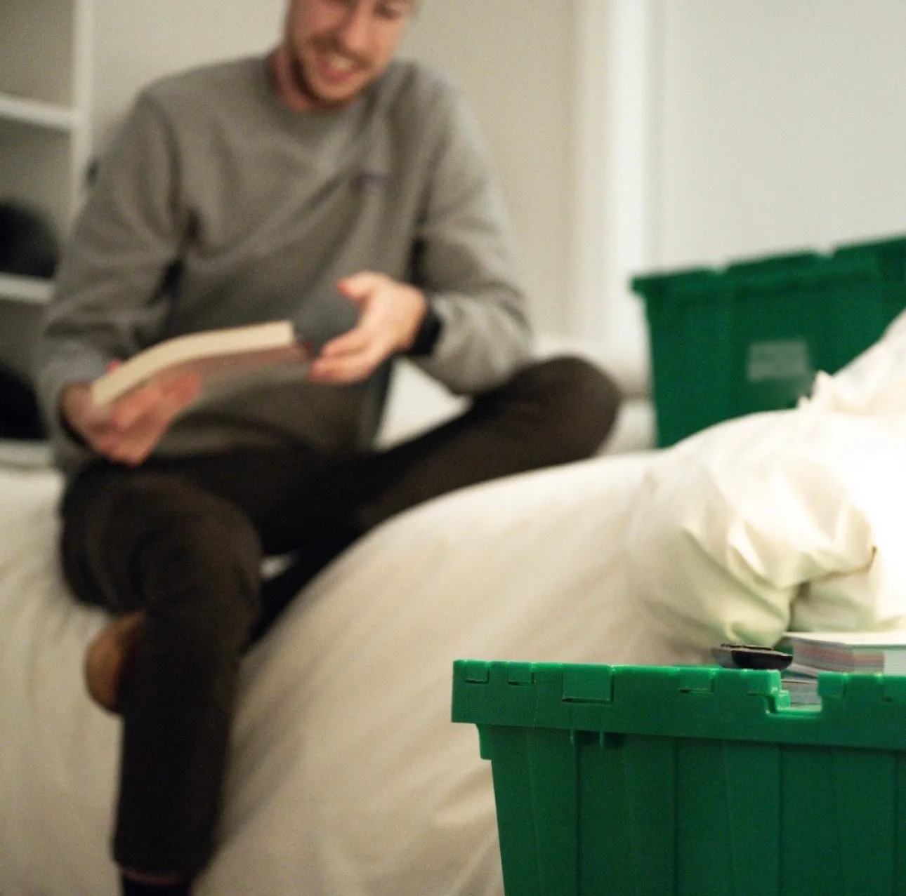 Soft-focus photo of a person packing a book at home beside green Frogbox bins