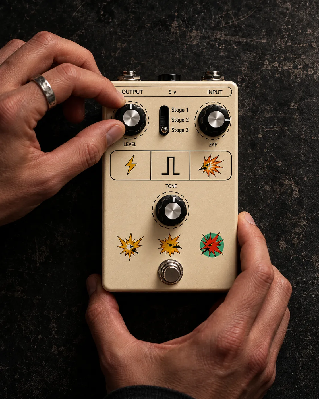 Hands adjusting the Level control on the ZAP + EVOLVE pedal against a dark textured surface.
