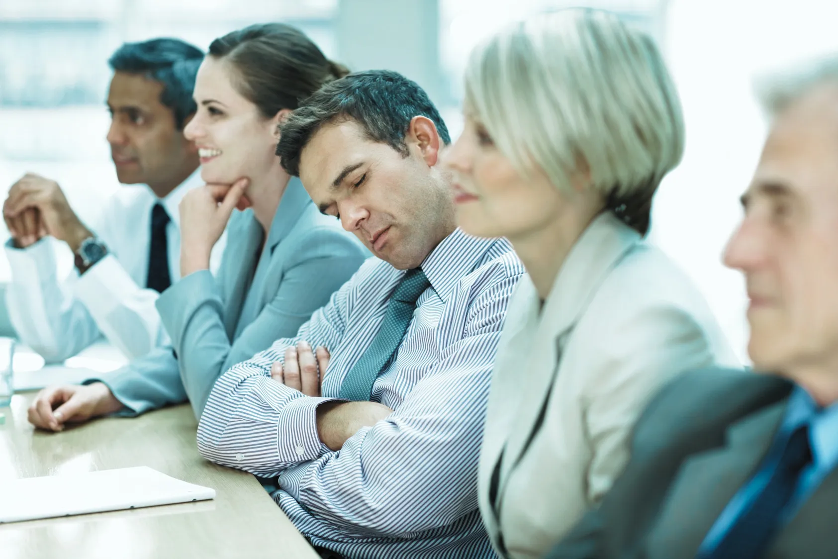 People attending a presentation, with a man sitting in the centre with his eyes closed.