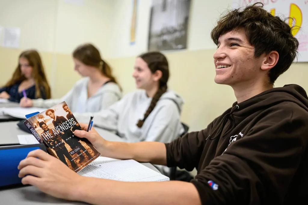 Student pasrticipating in class discussion, holding a book