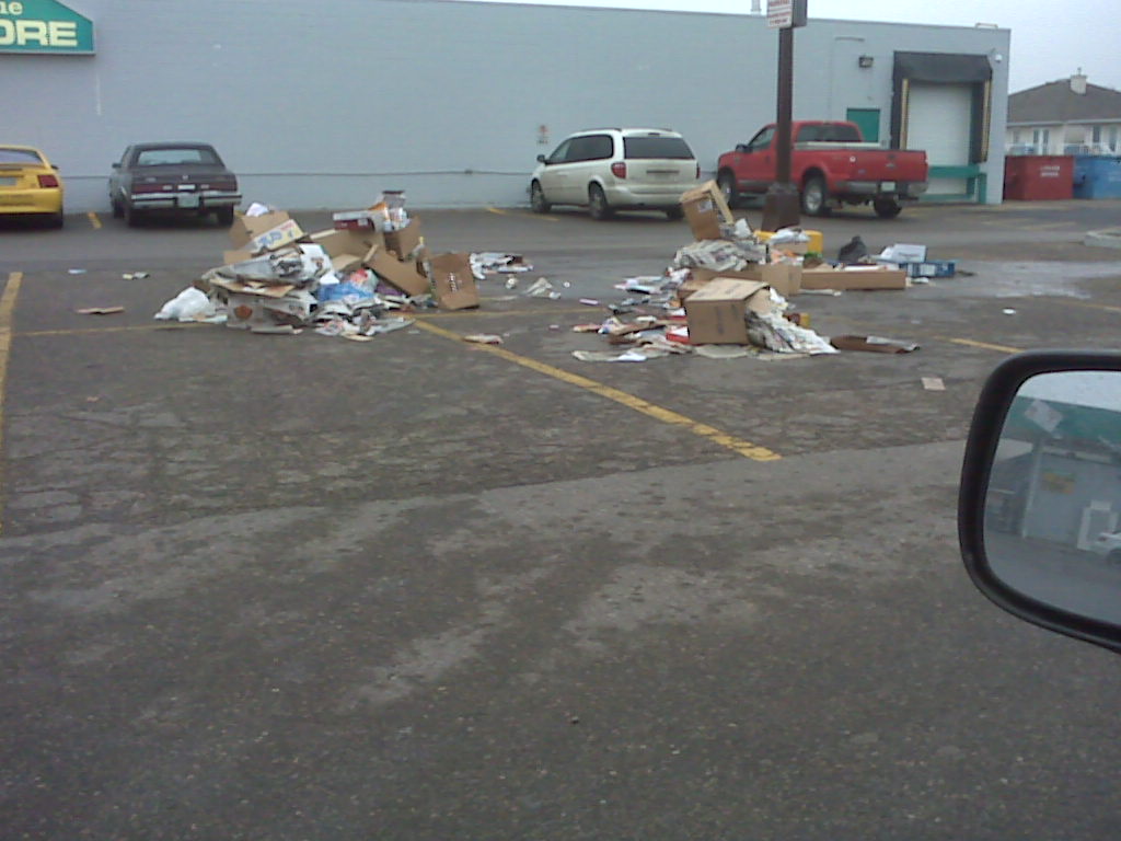 pile of recycling in a parking lot where the recycling container used to be