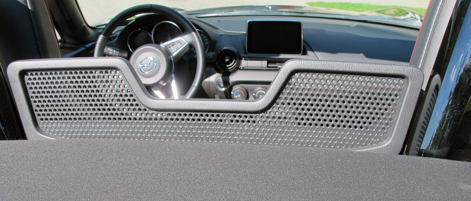 The soft top on the MX-5 is easily raised and lowered by one hand and features a glass rear window with defroster and includes a draft blocker between the seats.