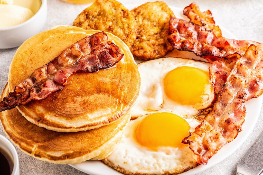 Healthy Full American Breakfast with Eggs Bacon Pancakes and Latkes.