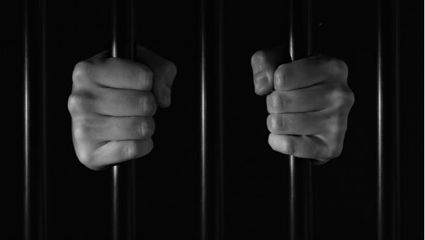 hands holding jail cell bards BW 600 x 370.jpg