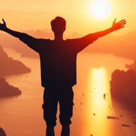 A silhouette of a man displaying emotional discipline as he stretches out his arms against a scenic river.