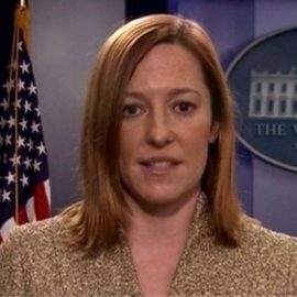 Jen Psaki in the White House briefing room in front of an American flag.