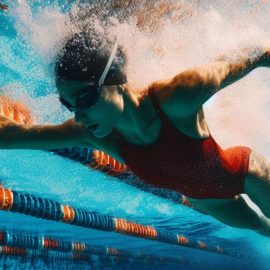 A woman swimming laps underwater in a public pool.