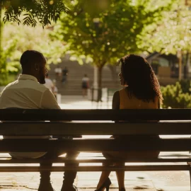A man and woman sitting on a park bench having a conversation