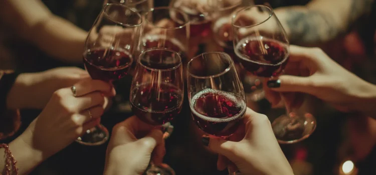 A group of hands toasting with glasses of red wine at Christmas while having a peaceful holiday celebration