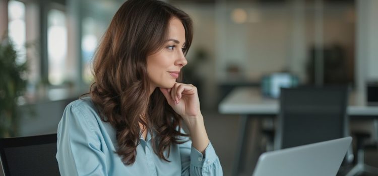 Scott Galloway: Career Advice From The Algebra of Happiness A woman with a light blue shirt and long brown hair sitting at a desk in an office contemplates career advice