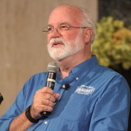 Greg Boyle holding a microphone and talking about gang intervention