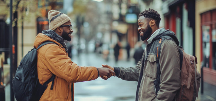 Two men on the street showing how to start a good conversation by shaking hands