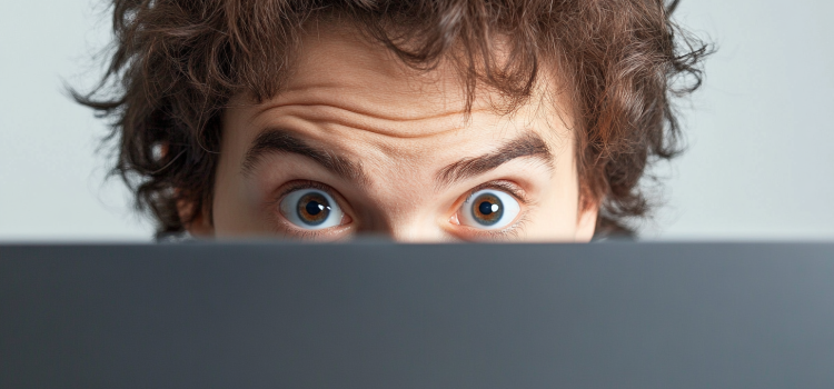 AI Manipulation: Yuval Noah Harari on the Threat & Its Solution A man with a surprised expression behind a laptop illustrates AI manipulation