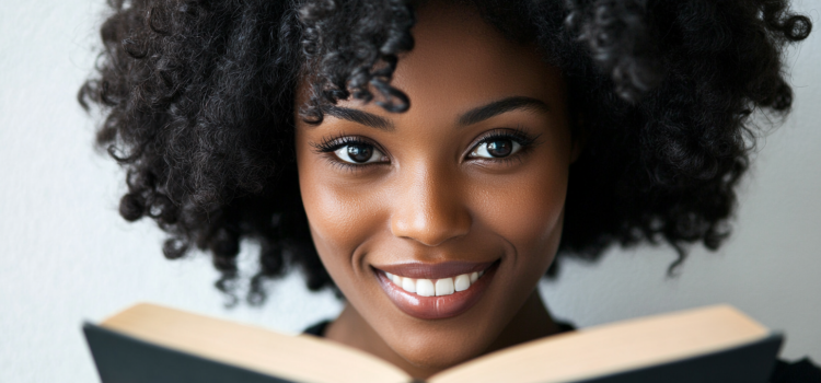 A woman with curly hair smiling and holding an open book
