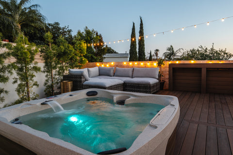 Hot tub with blue interior lighting in a nice backyard at dusk