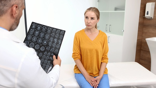 Doctor showing a woman brain scan images during a medical consultation in an exam room.