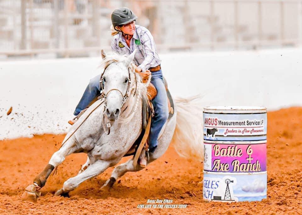 Liz Herrin running a grey horse at a barrel race.