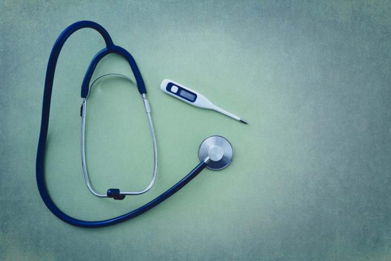 Stethoscope with digital thermometer on green background