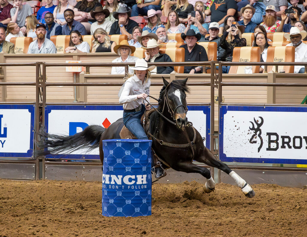 Morgan Bagnell rides a black horse around a barrel