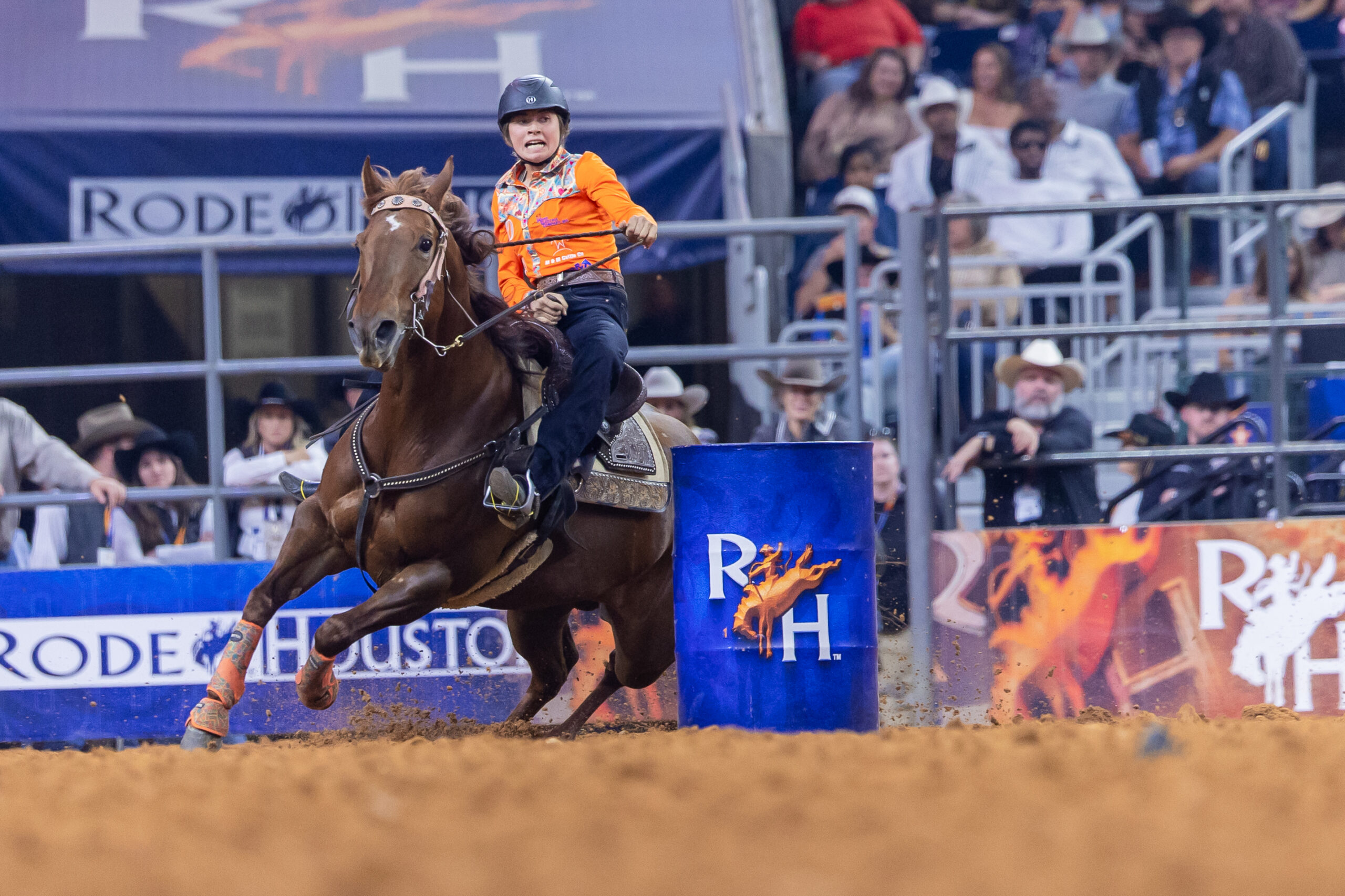 Loralee Ward turns a barrel at RodeoHouston in an orange shirt